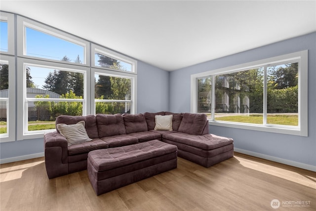 living area featuring plenty of natural light, wood finished floors, lofted ceiling, and baseboards