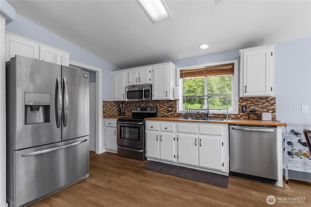 kitchen featuring stainless steel appliances, a sink, white cabinetry, tasteful backsplash, and dark wood-style flooring
