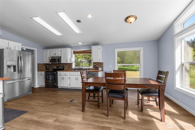 dining space featuring wood finished floors, lofted ceiling, and recessed lighting