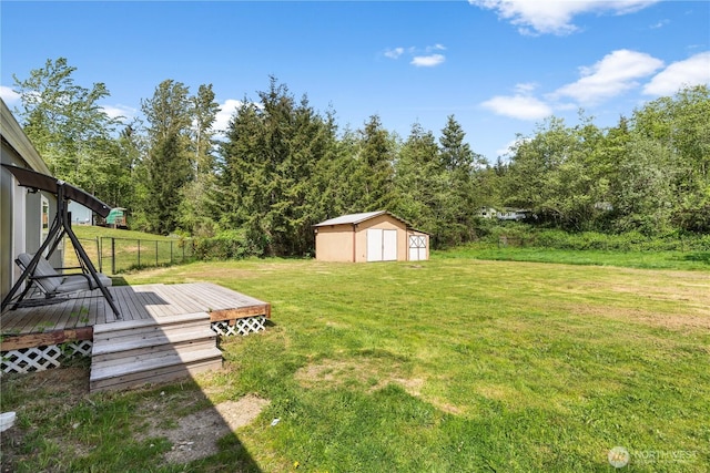 view of grassy yard with a shed, a wooden deck, and an outbuilding