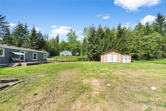 view of yard featuring a shed, a wooden deck, and an outbuilding