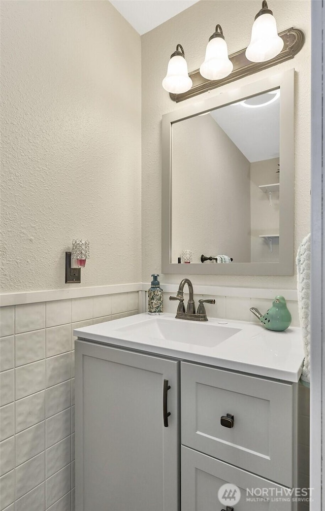 10822 SE 260th St Unit 2B1, Kent, WA 98030 - bathroom featuring a textured wall, tile walls, wainscoting, and vanity