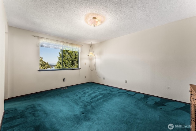 empty room featuring carpet floors, a textured ceiling, baseboards, and visible vents