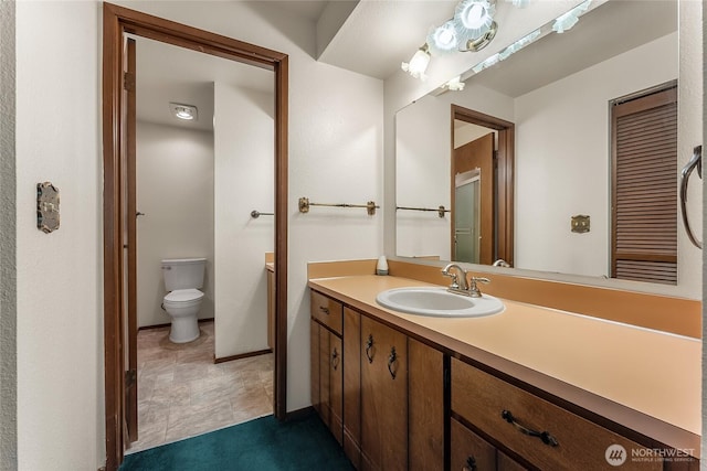 bathroom with vanity, baseboards, and toilet