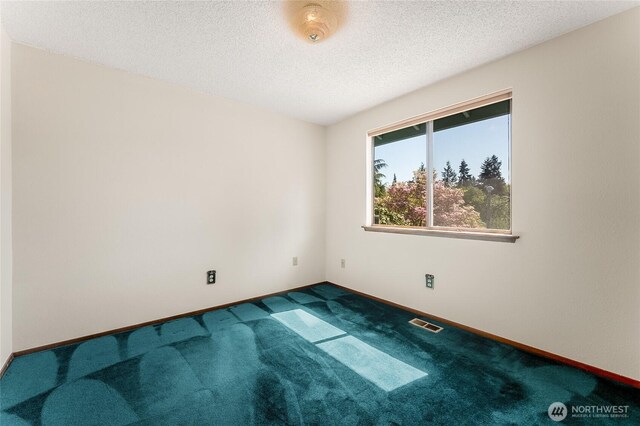 carpeted empty room with baseboards, a textured ceiling, and visible vents