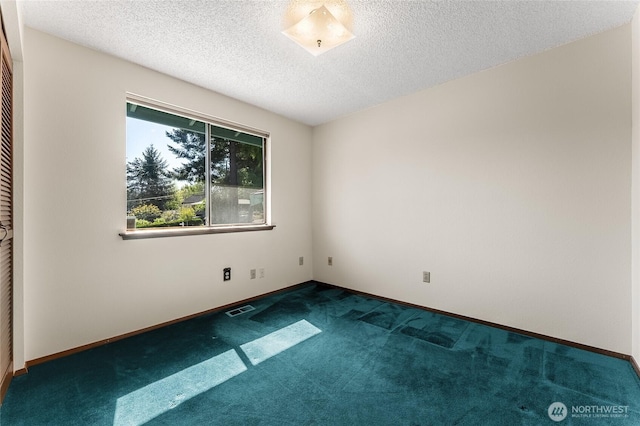 unfurnished room featuring baseboards, carpet, a textured ceiling, and visible vents