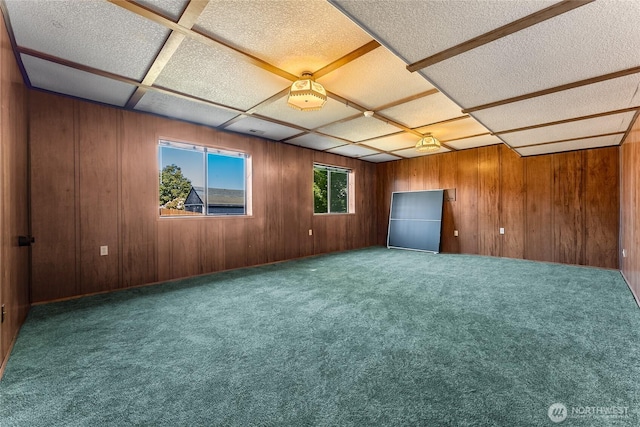 carpeted spare room with wooden walls and a textured ceiling
