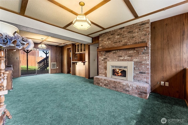 unfurnished living room with visible vents, carpet, wooden walls, and a fireplace