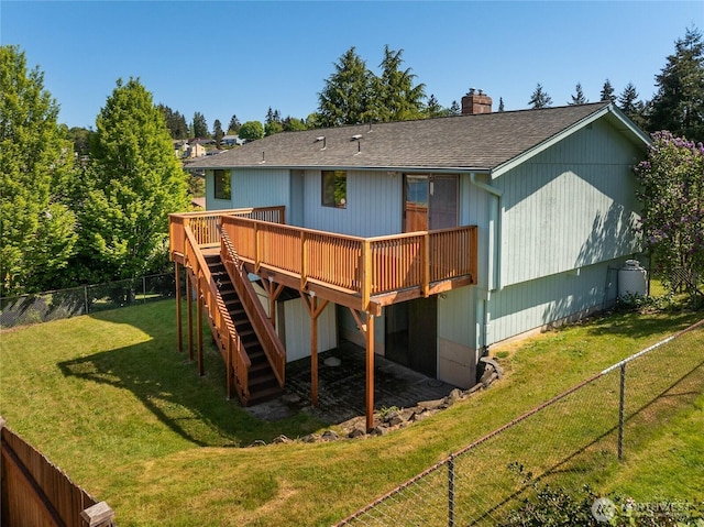 back of property featuring a deck, stairway, a fenced backyard, a chimney, and a lawn