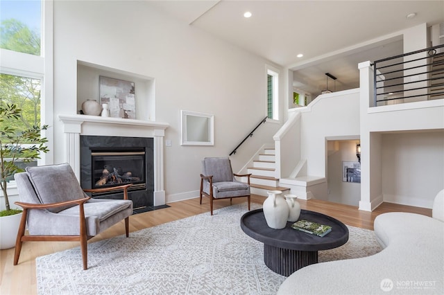 living room with healthy amount of natural light, wood finished floors, a tile fireplace, stairway, and recessed lighting