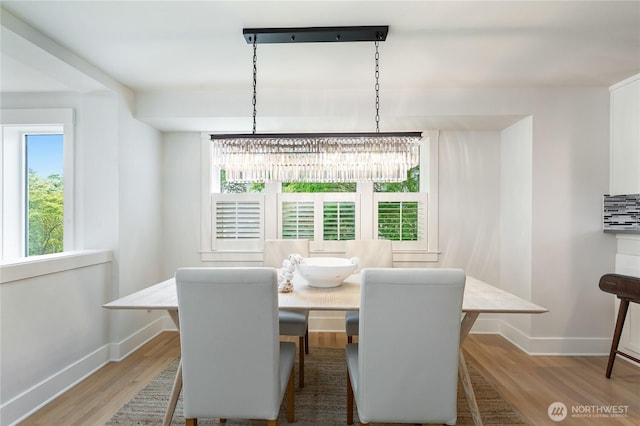dining area with baseboards, a chandelier, and light wood-type flooring