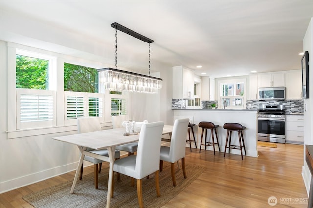 dining room featuring light wood finished floors, recessed lighting, and baseboards