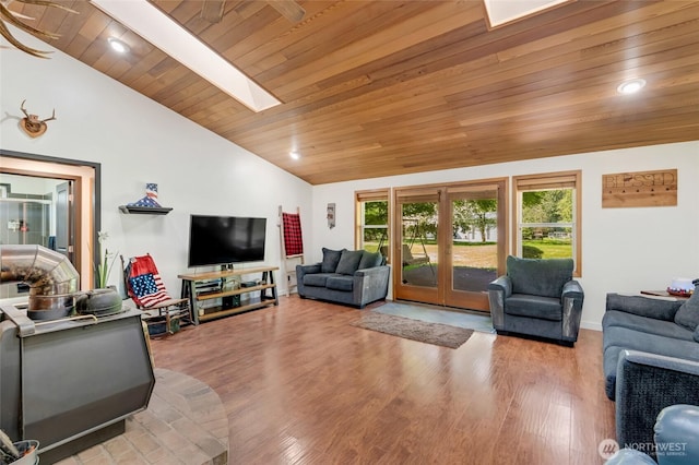 living room featuring lofted ceiling, wood ceiling, wood finished floors, a skylight, and baseboards