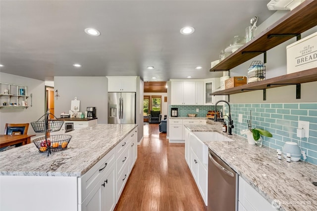 kitchen with stainless steel appliances, recessed lighting, a sink, tasteful backsplash, and light stone countertops