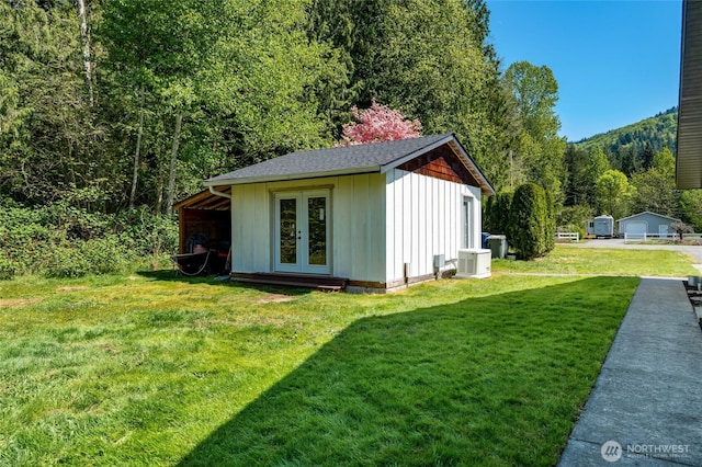 view of outbuilding with central AC, a wooded view, french doors, and an outbuilding