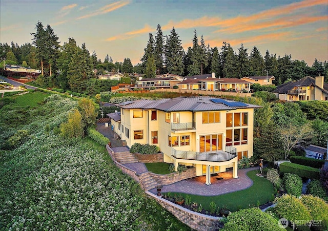 7212 164th St SW, Edmonds, WA 98026 - back of property at dusk with a balcony, stucco siding, a standing seam roof, a patio area, and a metal roof