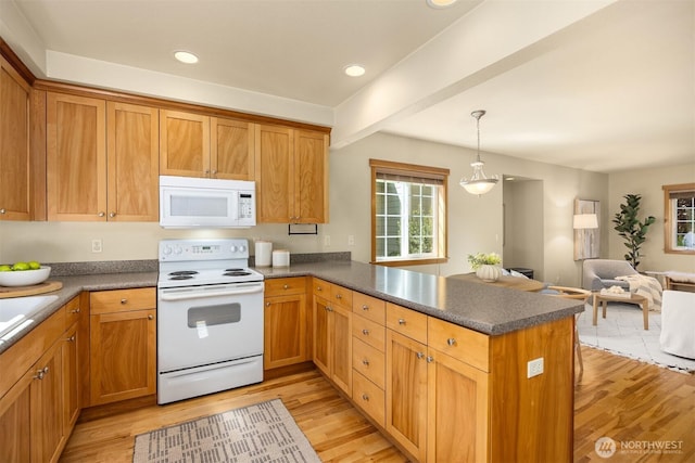 kitchen featuring white appliances, a peninsula, light wood-type flooring, and plenty of natural light