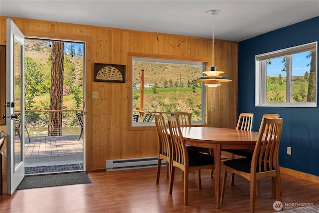 69 Ross Rd, Twisp, WA 98856 - dining area featuring healthy amount of natural light, wood walls, a baseboard radiator, wood finished floors, and baseboards