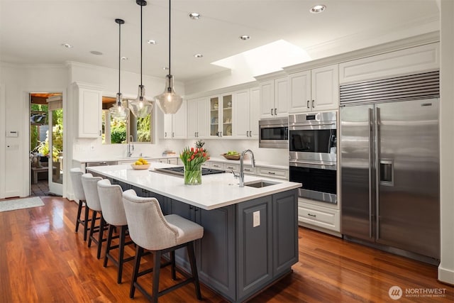 kitchen with built in appliances, a sink, white cabinets, crown molding, and recessed lighting