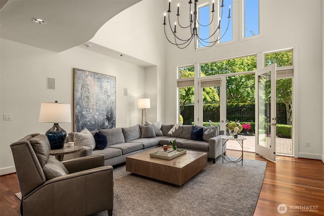 living area with wood finished floors, baseboards, a chandelier, and a high ceiling
