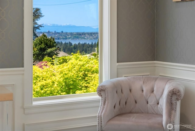 living area with wallpapered walls and a wainscoted wall