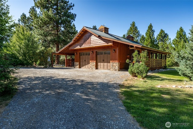 exterior space with a chimney, board and batten siding, a lawn, a garage, and stone siding