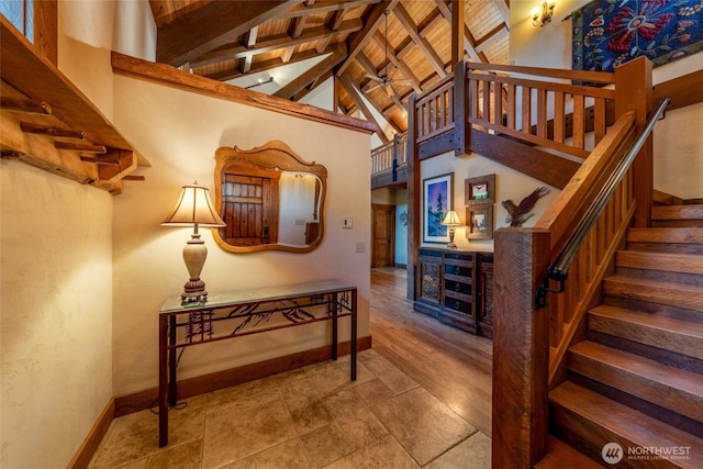 stairway featuring baseboards, beamed ceiling, and high vaulted ceiling