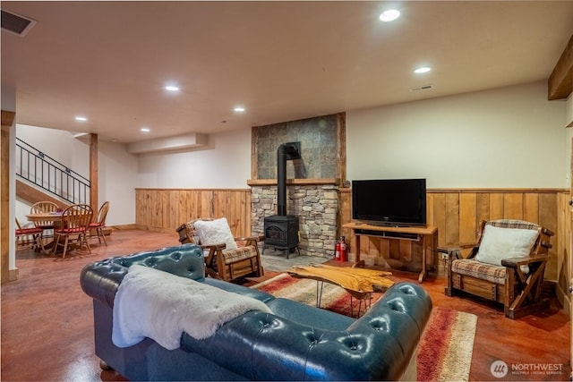 living area featuring a wood stove, a wainscoted wall, visible vents, and recessed lighting