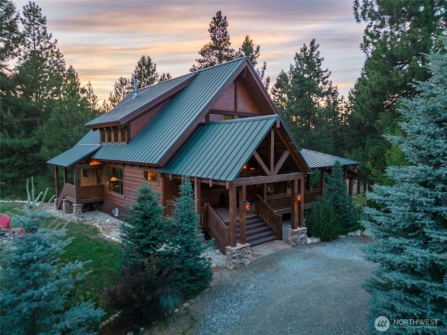 log home with covered porch and metal roof