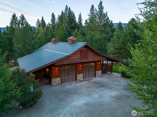 garage featuring a wooded view, dirt driveway, and a detached garage