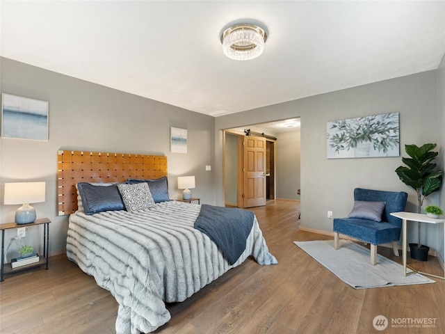 21608 186th Ave E, Orting, WA 98360 - bedroom featuring a barn door, wood finished floors, and baseboards