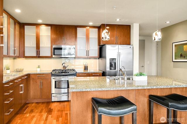 2121 Terry Ave Unit N1203, Seattle, WA 98121 - kitchen featuring appliances with stainless steel finishes, a sink, light wood-style floors, a kitchen bar, and recessed lighting