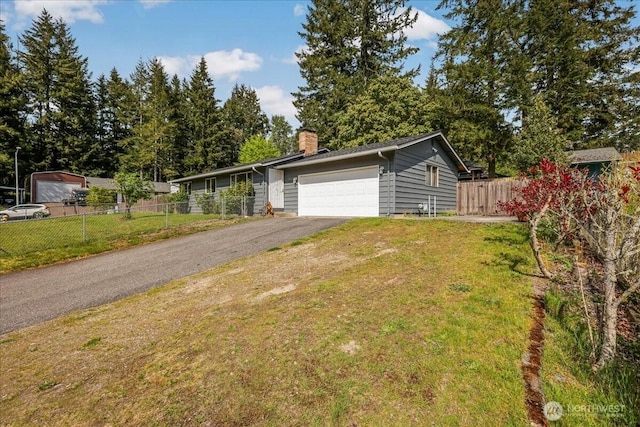 view of front of house featuring a chimney, fence, an attached garage, aphalt driveway, and a front lawn