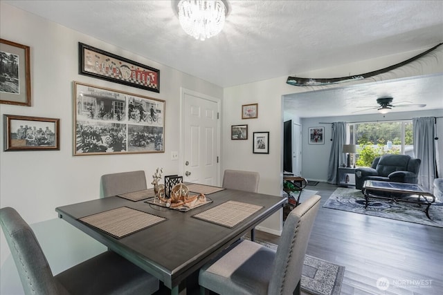 dining area featuring wood finished floors and ceiling fan with notable chandelier