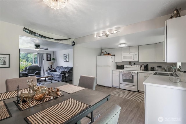 kitchen with a sink, white appliances, ceiling fan, light wood-style flooring, and light countertops