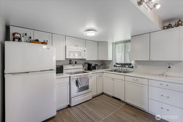 kitchen featuring white cabinetry, wood finished floors, a sink, and white appliances