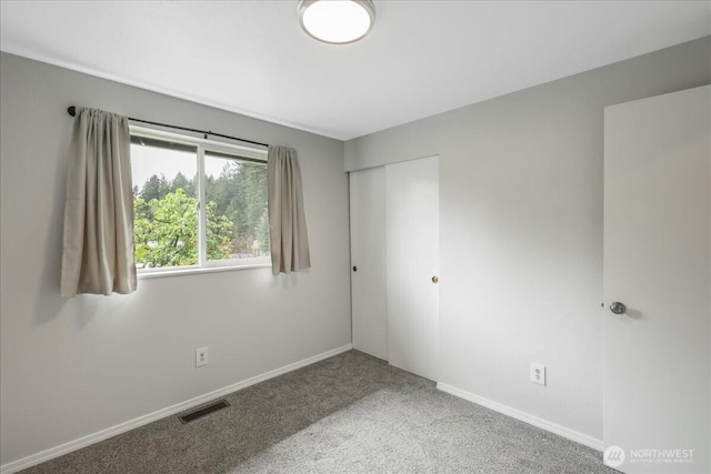 unfurnished bedroom with carpet, a closet, baseboards, and visible vents
