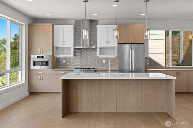kitchen featuring a wealth of natural light, stainless steel appliances, wall chimney exhaust hood, and a sink