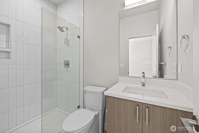 full bath with toilet, a tile shower, and vanity