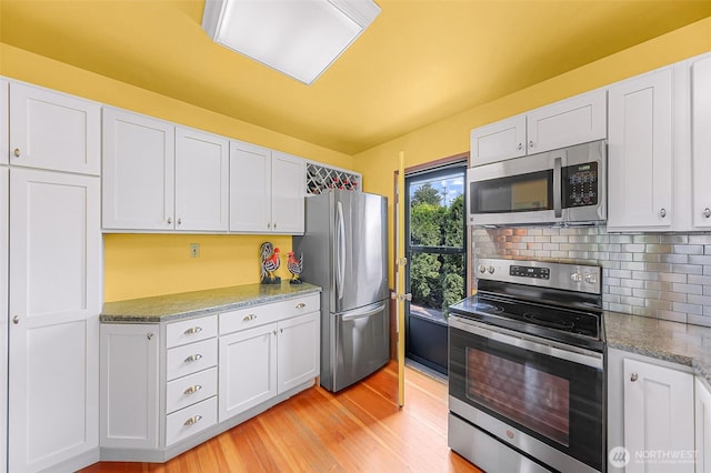 832 Elm Ave, Blaine, WA 98230 - kitchen with appliances with stainless steel finishes, light wood-style flooring, white cabinetry, tasteful backsplash, and light stone countertops