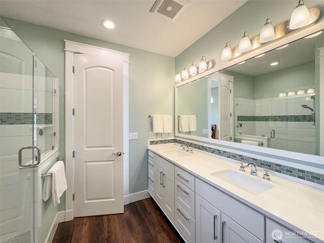 bathroom featuring a sink, a stall shower, visible vents, and wood finished floors