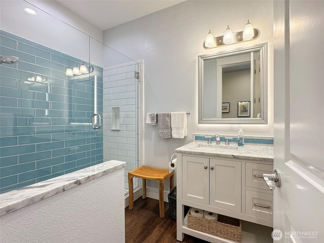 full bath with vanity, wood finished floors, and a tile shower