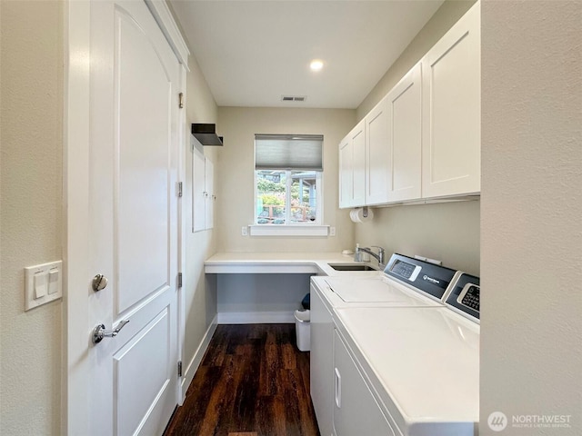 laundry room featuring a sink, cabinet space, washer and clothes dryer, visible vents, and dark wood-type flooring