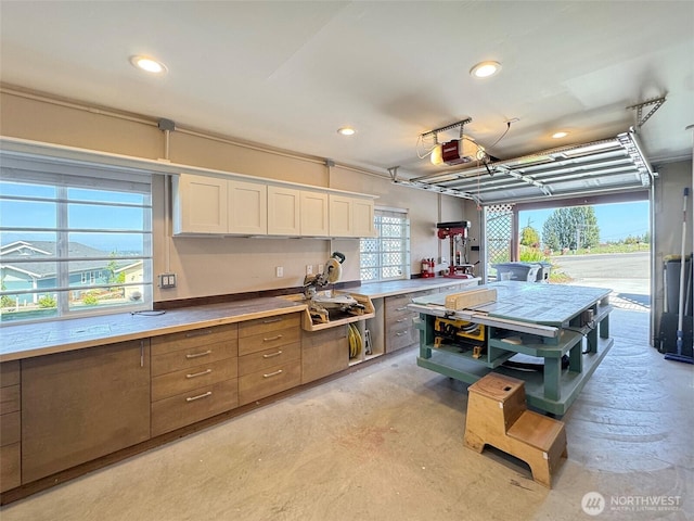 kitchen with brown cabinetry, recessed lighting, concrete flooring, and white cabinets