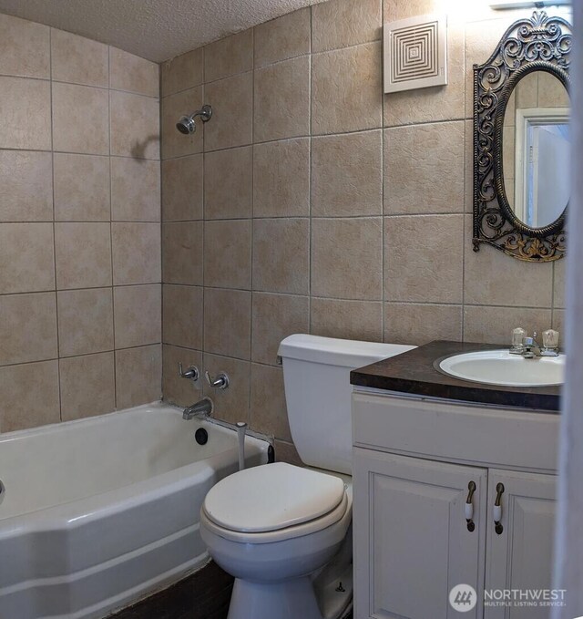 1225 W 5th St, Port Angeles, WA 98363 - full bathroom featuring vanity, tile walls, a textured ceiling, and toilet