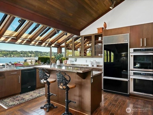 4400 E Mercer Way, Mercer Island, WA 98040 - kitchen featuring black appliances, vaulted ceiling, dark wood-style floors, a kitchen island, and a breakfast bar area