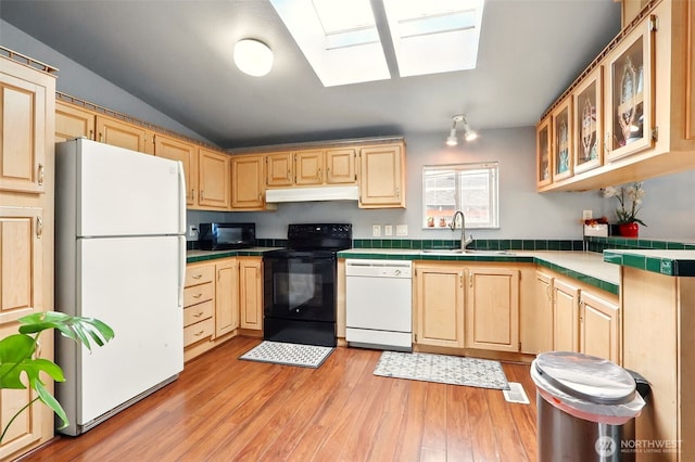 kitchen with black appliances, a sink, tile countertops, light brown cabinetry, and a skylight