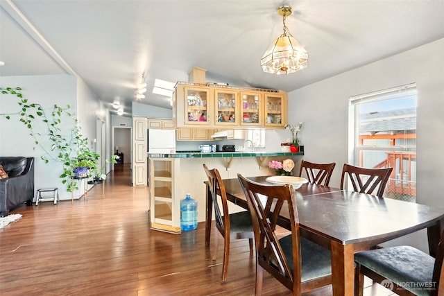 dining space with wood finished floors, lofted ceiling, and a chandelier