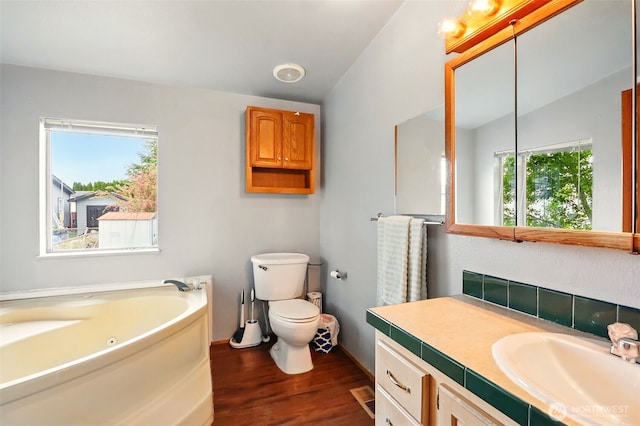 full bath featuring wood finished floors, toilet, a jetted tub, vanity, and baseboards