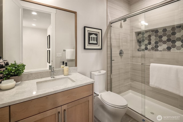 full bathroom with a stall shower, vanity, and toilet